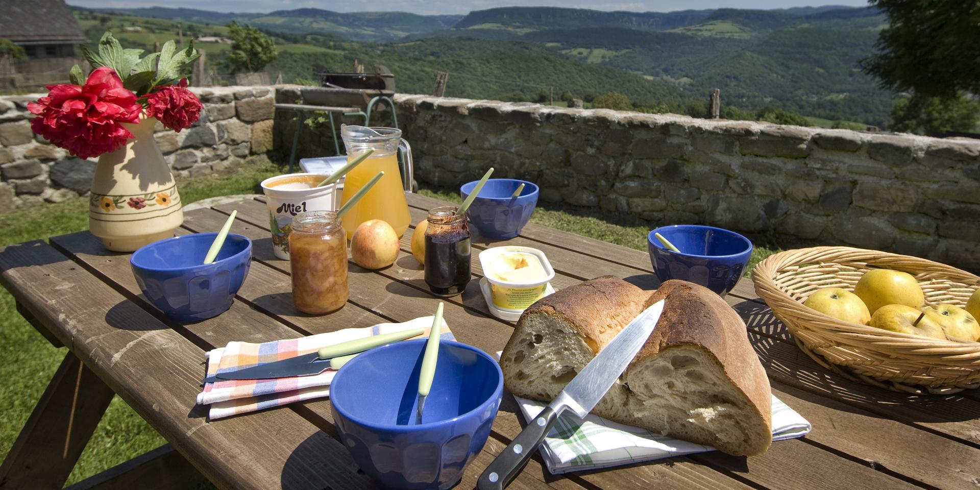 Breakfast on the terrace of an Aubrac gîte with local produce Bread, honey, jam, fruit ... and a beautiful panoramic view.