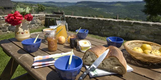 Petit déjeuner en terrasse d'un gîte sur l'Aubrac avec des produits locaux Pain, miel, confiture, fruits ... et une belle vue panoramique