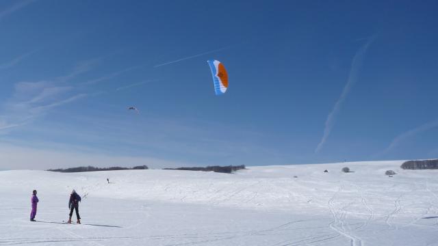 Personnes faisant du snowkite sur la neige au col de Bonnecombe sur l'Aubrac.