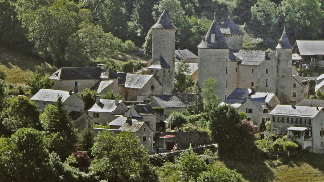 Saint Saturnin and its 14th-century castle at the foot of the Causse de Sauveterre cliffs in the Urugne valley.